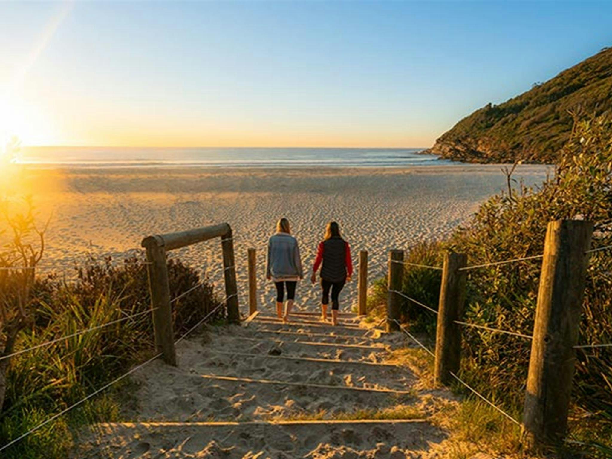 Two women walk towards a beach at sunrise, Booti Booti National Park. Photo credit: John Spencer