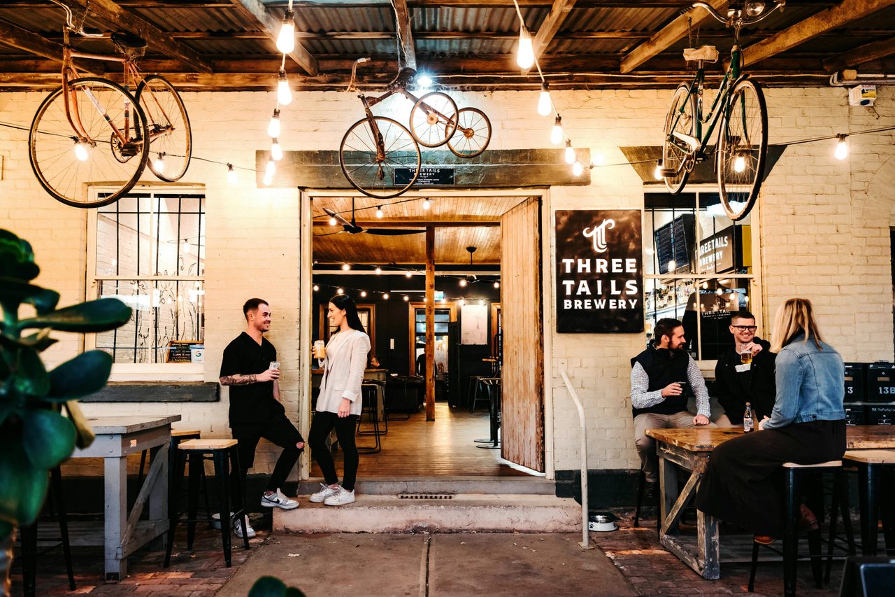 The front entrance to Three Tails Brewery, bikes hanging from ceiling, people conversing