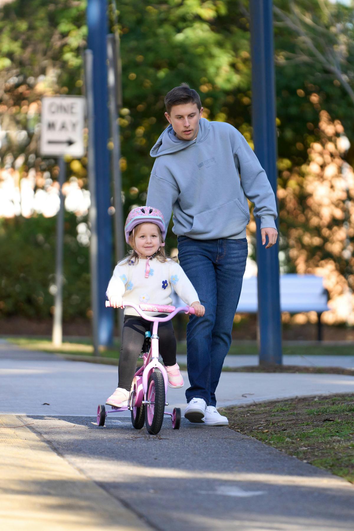 Father helping girl ride scoooter.