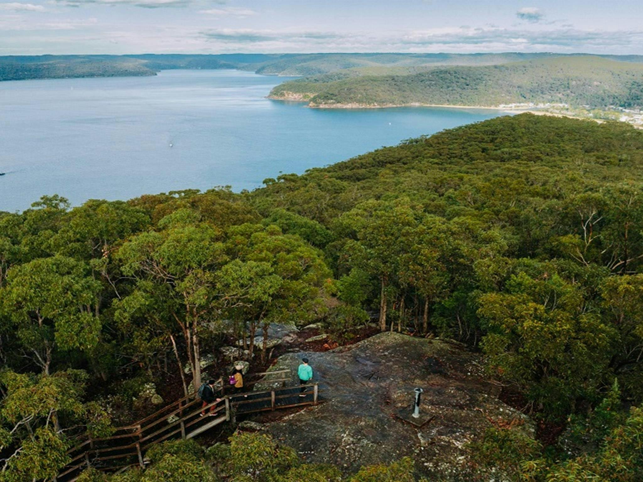 Aerial view of hikers along  Warrah Trig walking track framed by the picturesque Hawkesbury River.