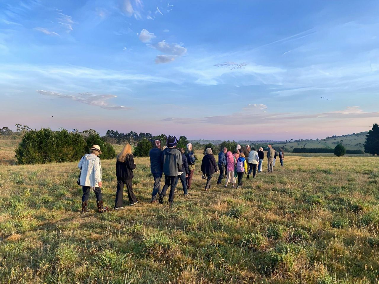 Á line of visitors traverse through fields at dusk