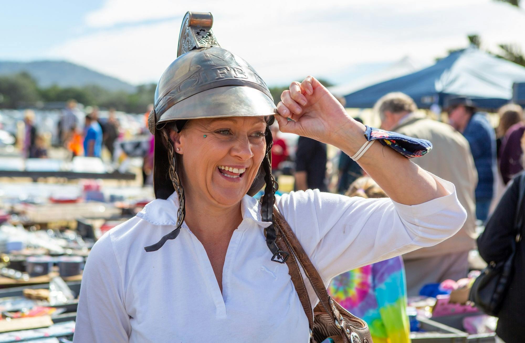 Women trying on a dress up helmet at a market stall