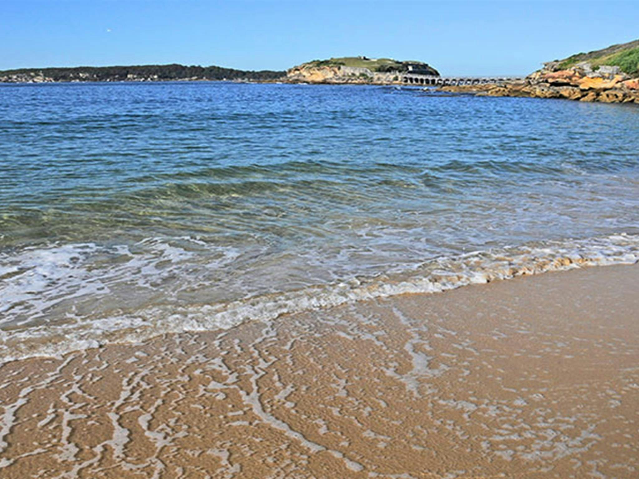 Gentle waves lap Congwong Beach, with Bare Island in background.  Photo: Kevin McGrath/OEH.