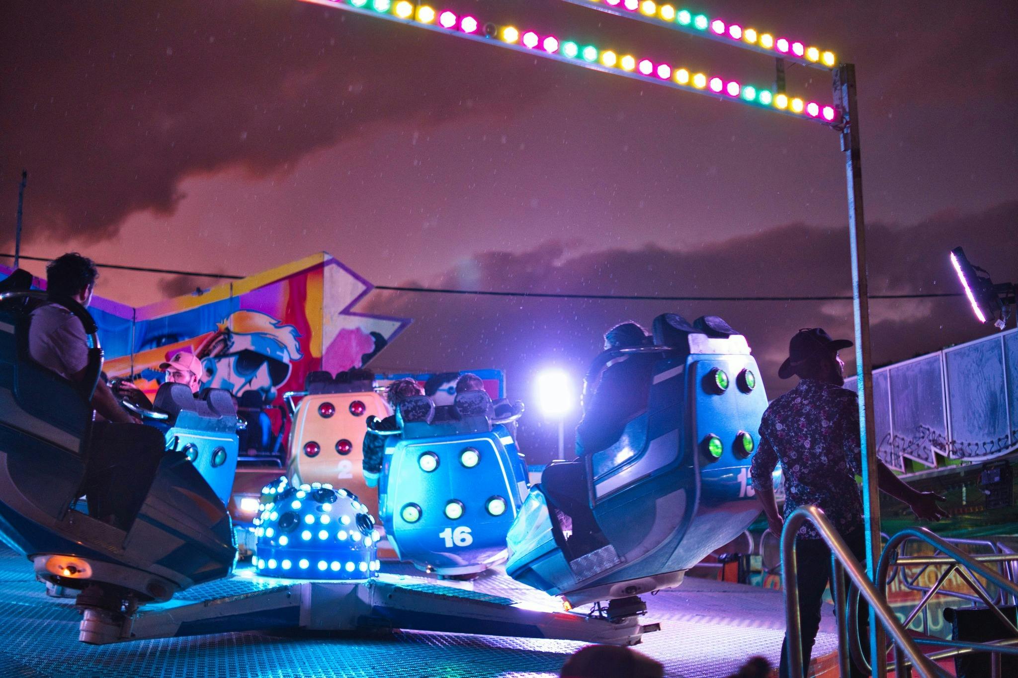 An amusement ride with colorful capsules in circular motion, people seated inside.