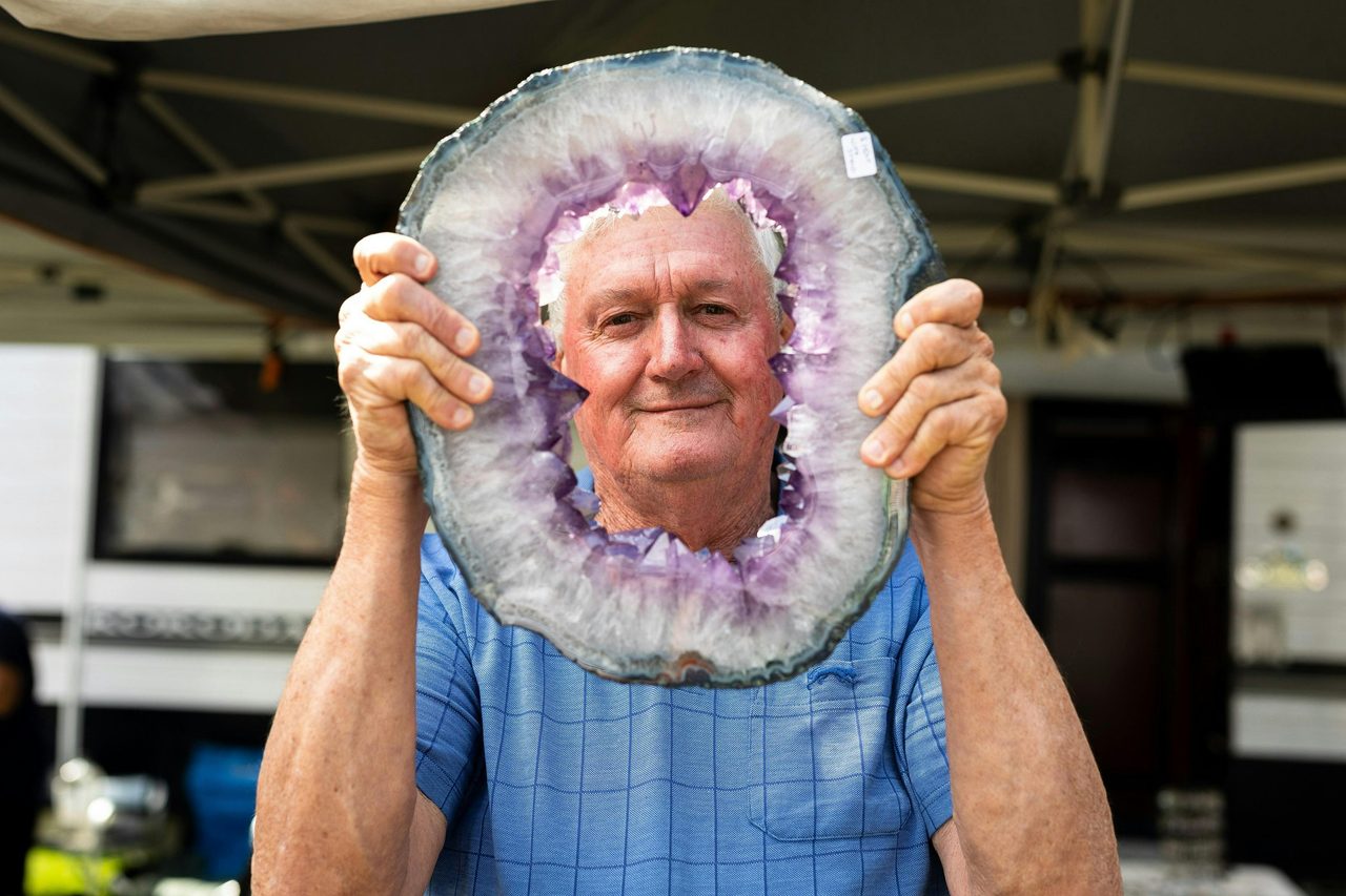 Outdoor trader holding large purple gemstone specimen