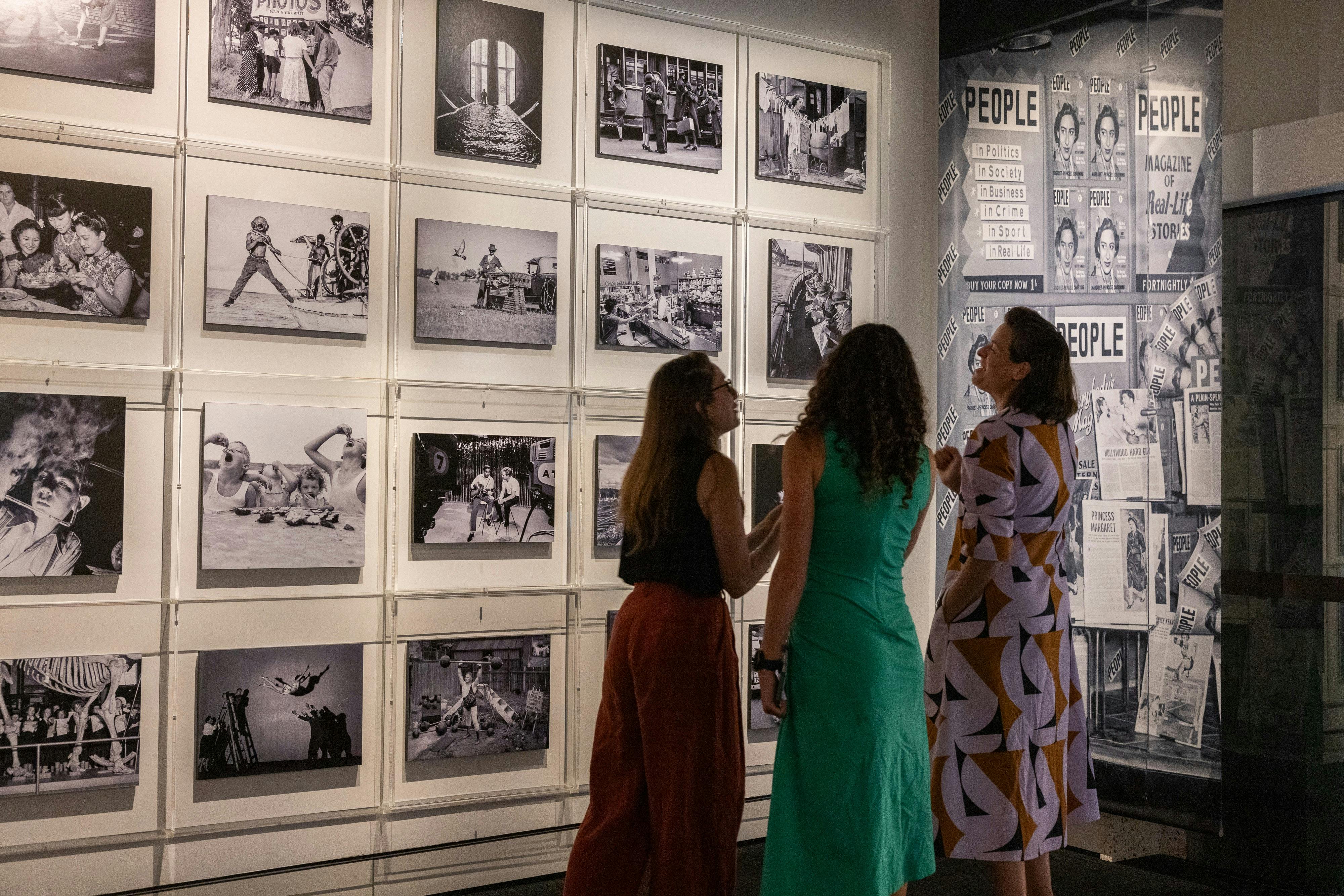 Three women talking in a photography exhibition