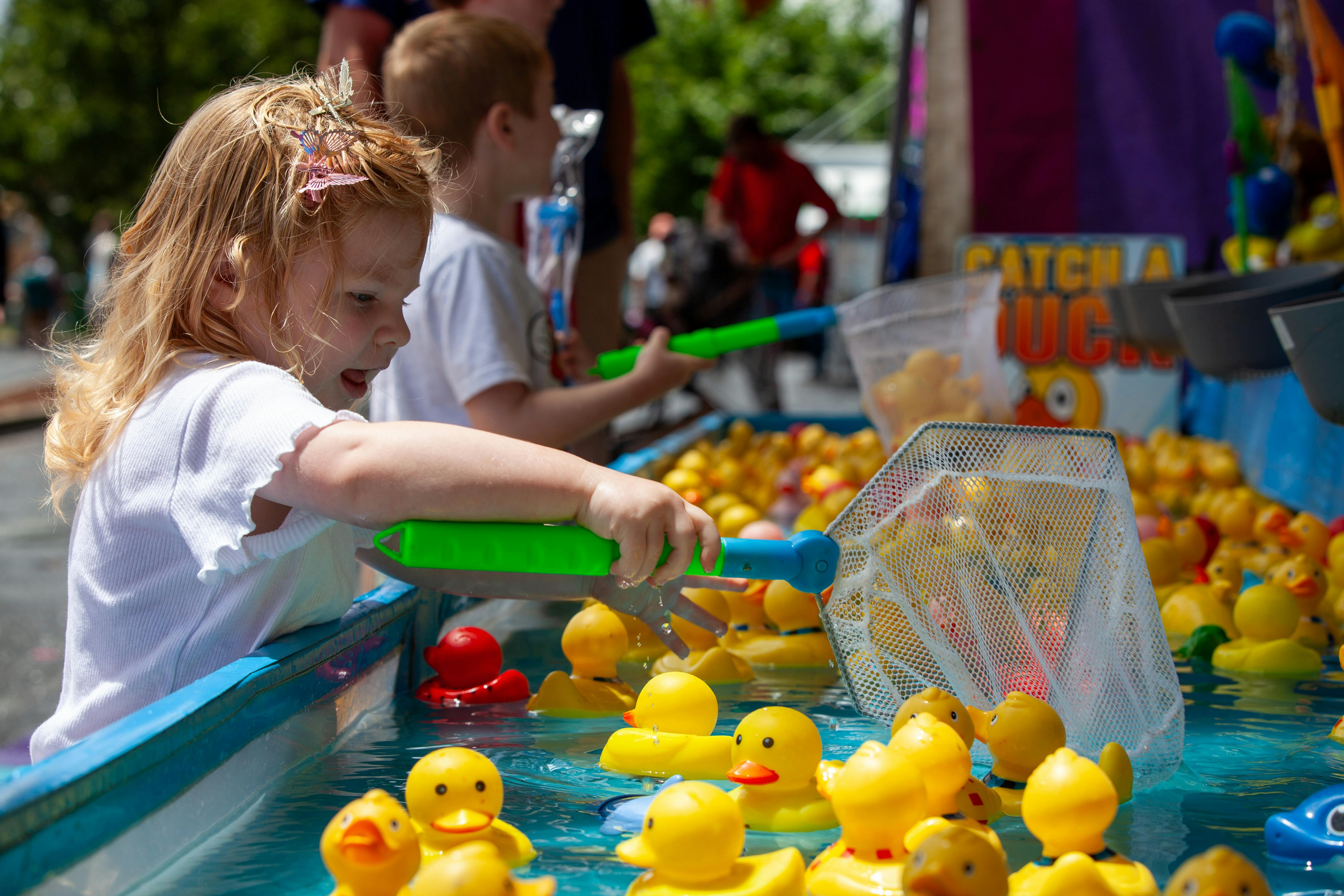 Child scooping rubber ducks at carnival game