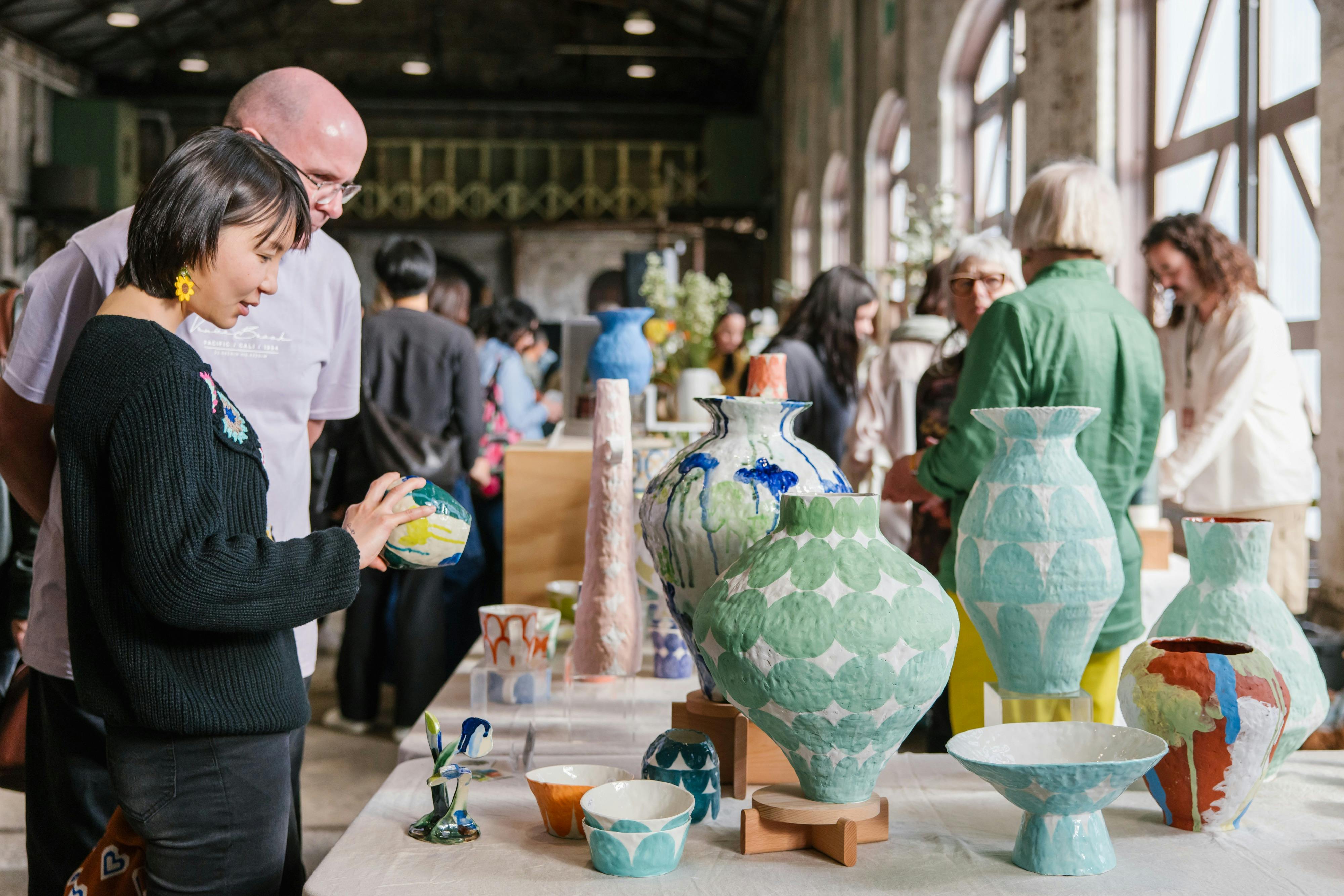 Visitors browse colourful ceramic pieces handmade by Susan Buret
