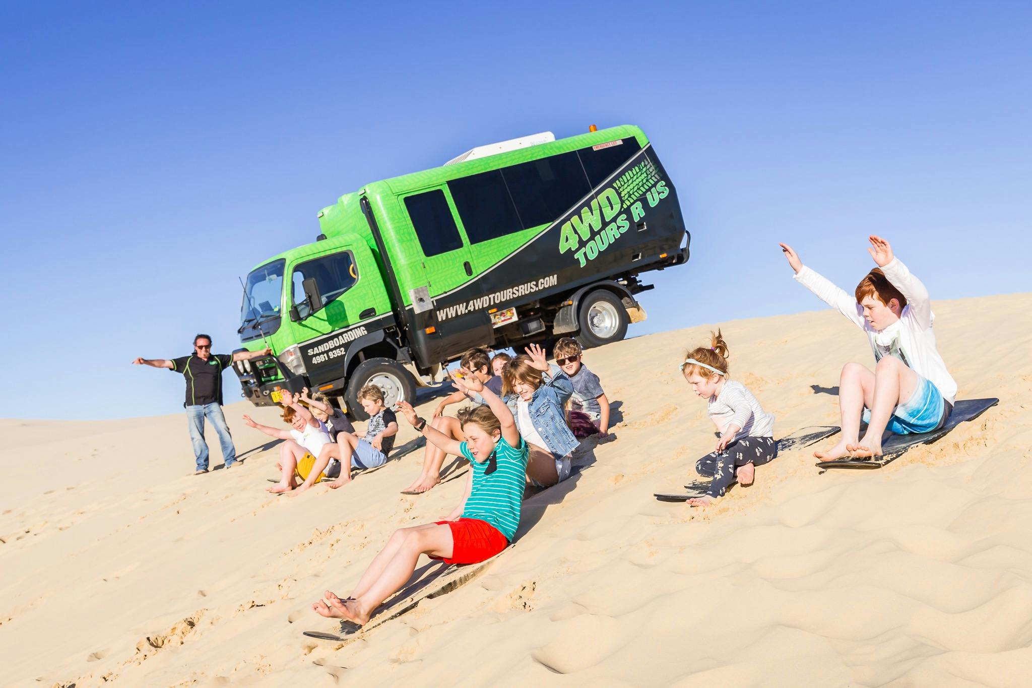 4WD Tours R Us bus parked on the sand with kids playing