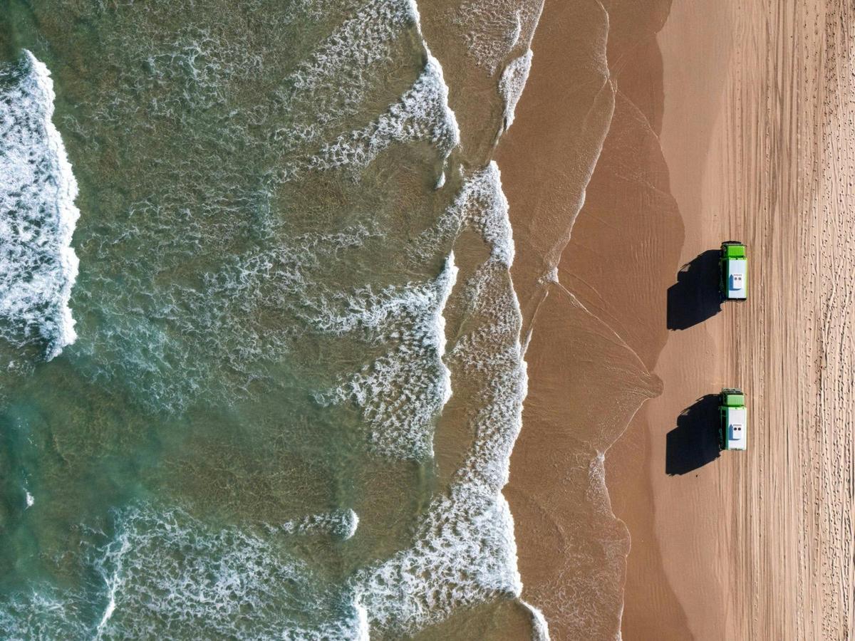 Two busses driving along the shore line