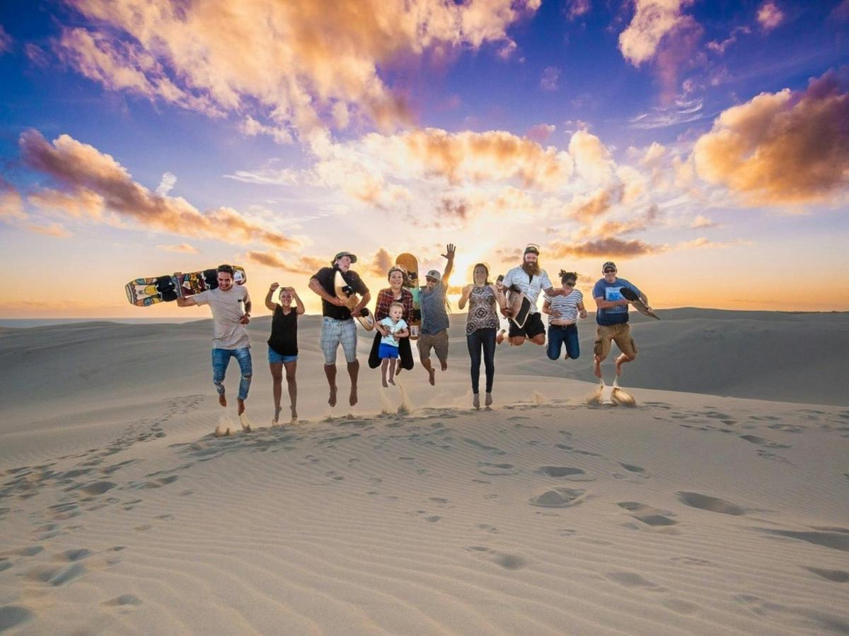 Group of Children and Adults jumping in the air on top of a sand dune
