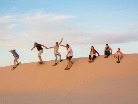 Group of Adults about to slide down the sand dunes