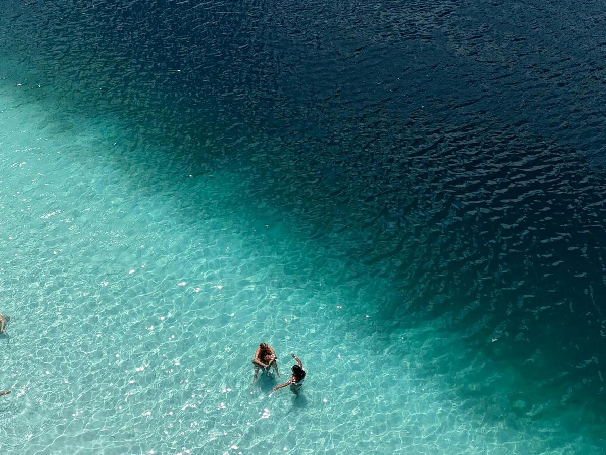 Aerial view of two swimmers in crystal-clear shallow turquoise water, Australia