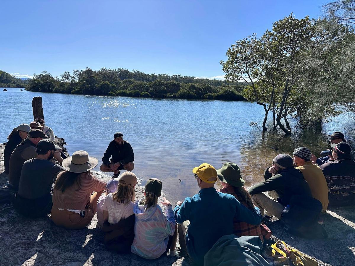 Tour group sitting by Narrawallee Creek listening to dreaming story