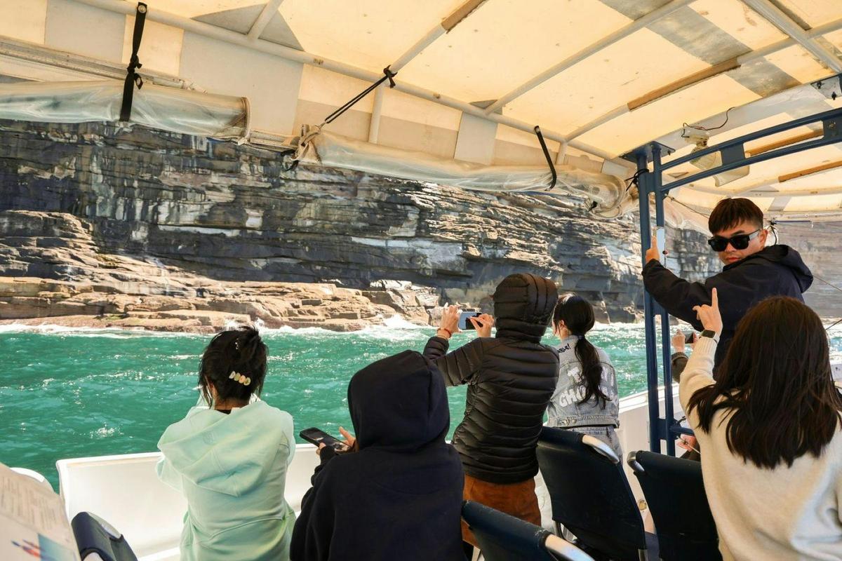 people on a boat taking photos of Sydney coastline