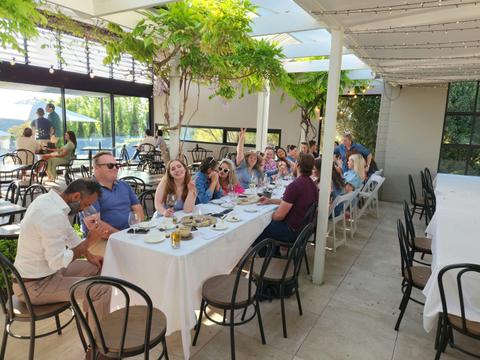A group of individuals gathered around a table, engaged in conversation and enjoying a meal together