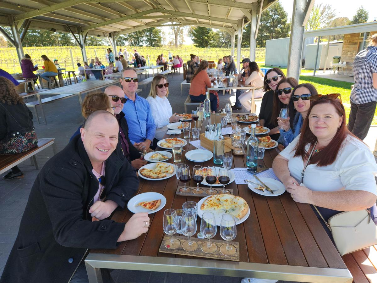 A group of people sitting at a table enjoying a meal together, with a variety of food and glasses of