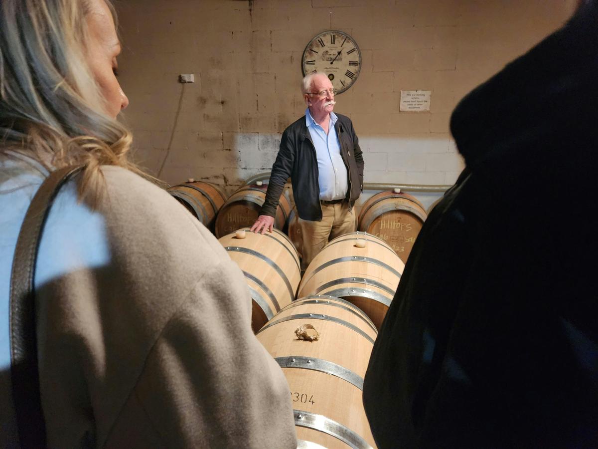 A man standing in front of a group of oak barrels