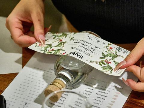 A person carefully places a label onto a bottle, ensuring it is aligned properly