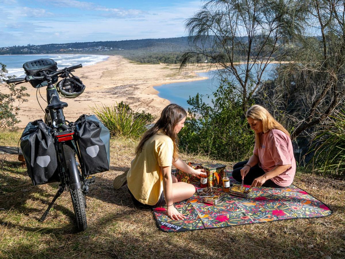 Guests enjoy the picnic with Tathra Beach in background