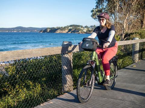 Guest cycling past Aslings Beach, Eden