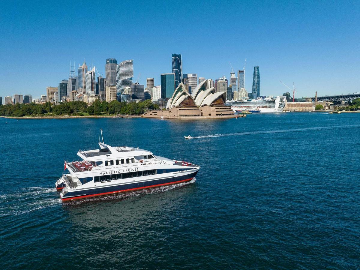 The luxury catamaran 'Magistic Two' cruising Sydney Harbour, with the Opera House and the iconic sky