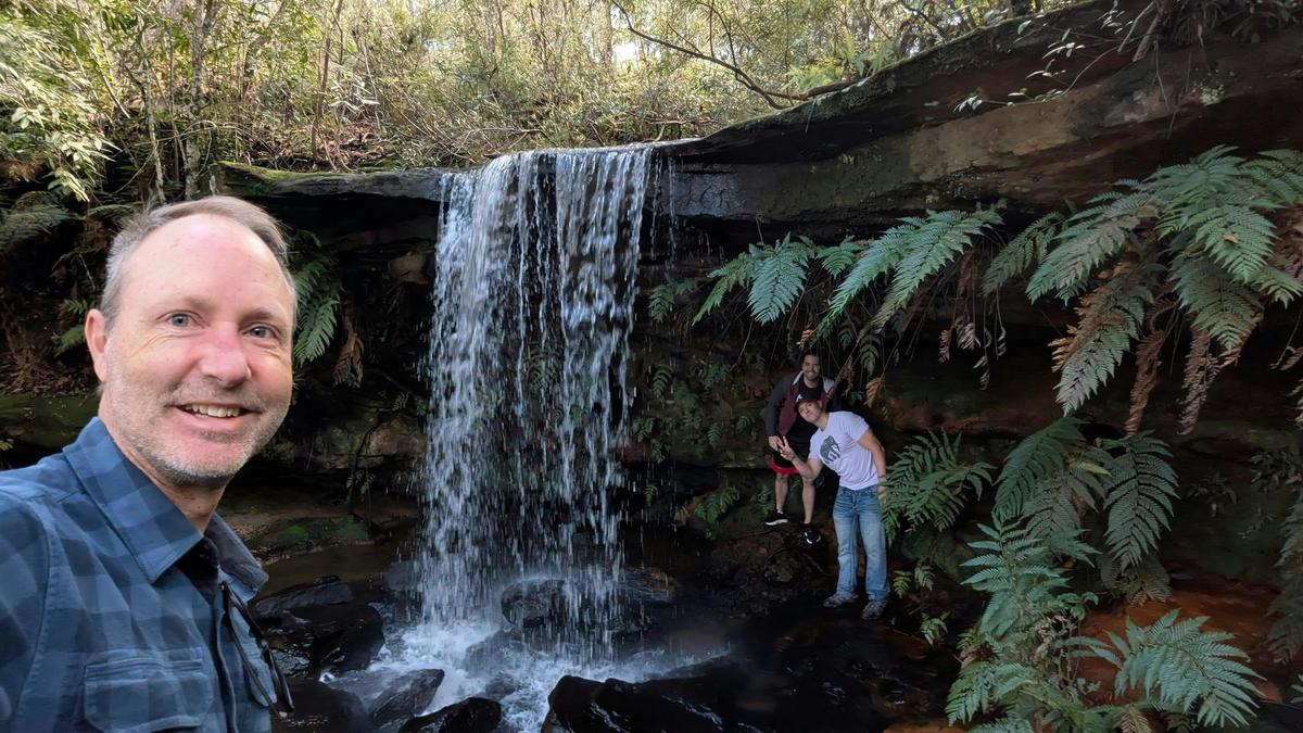 Standing under a waterfall on our Central Coast of NSW tour