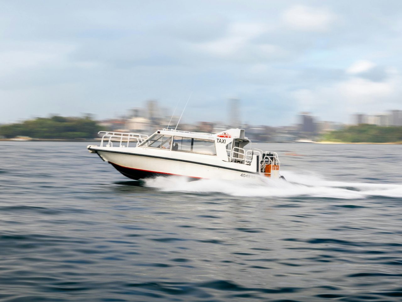 Water taxi travelling at speed through Sydney Harbour.