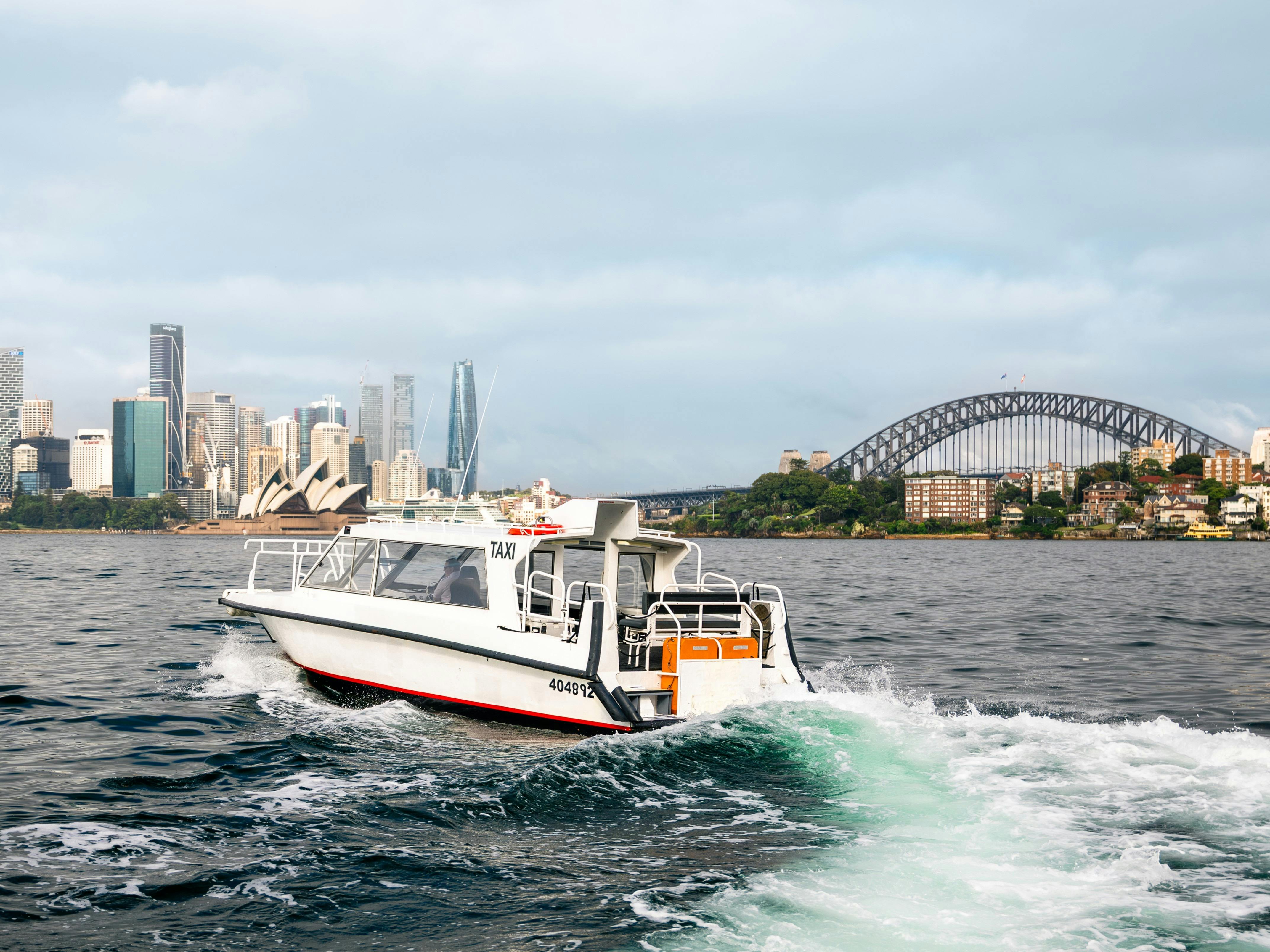 Water taxi turning in Sydney Harbour with Sydney Opera House behind.