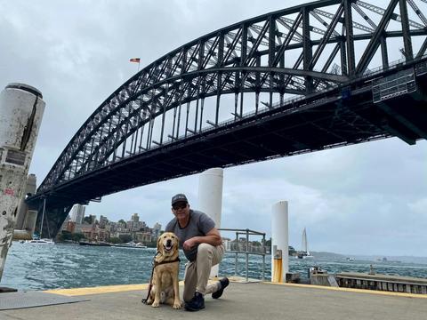 traveller and his Guide Dog pictured infront of the Sydney Harbour Bridge