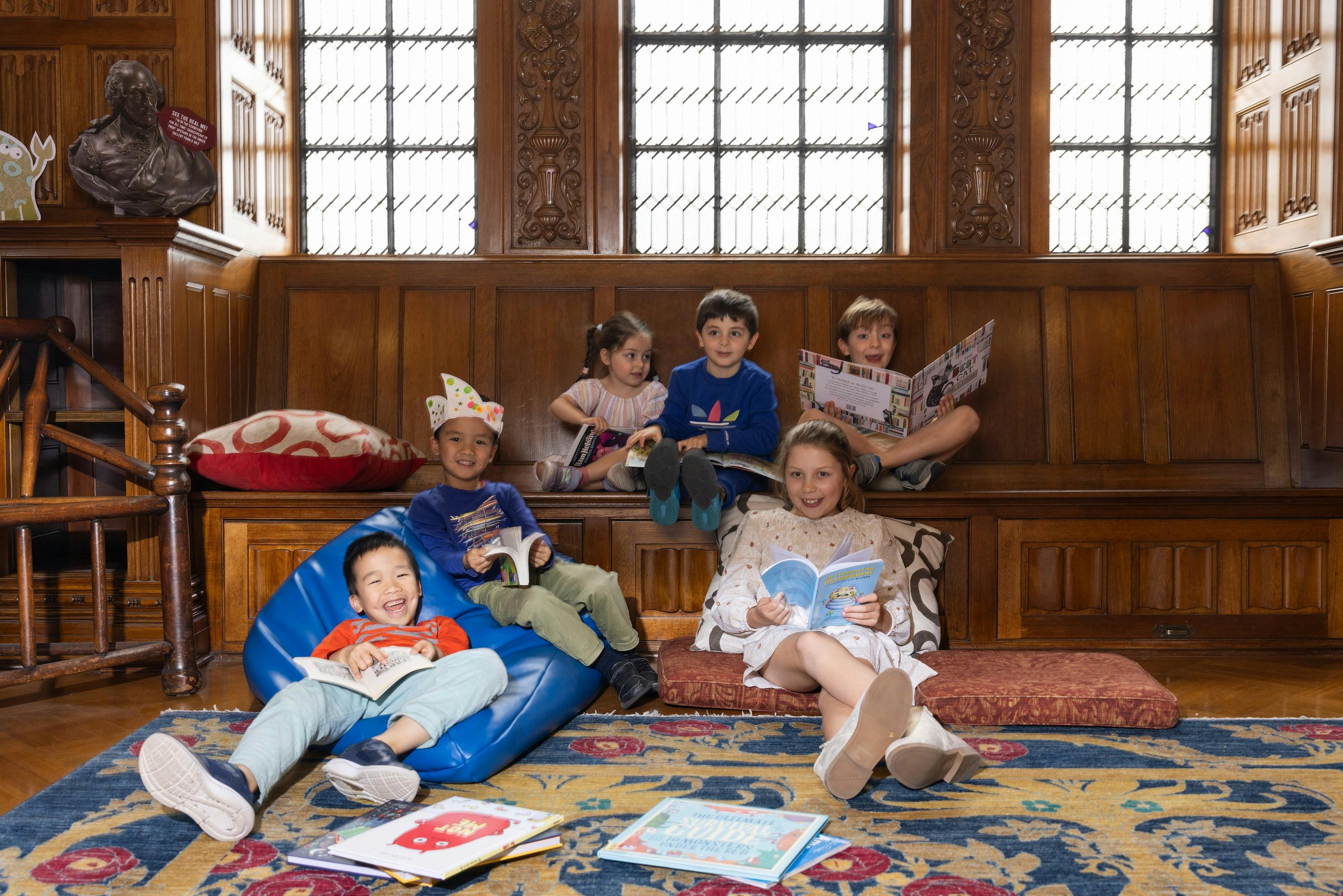 Children with books in an ornate room with engraved wood details.