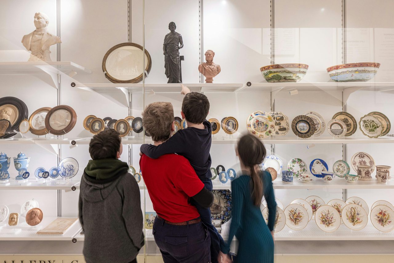 A father with three children standing in front of a display case full of curious objects