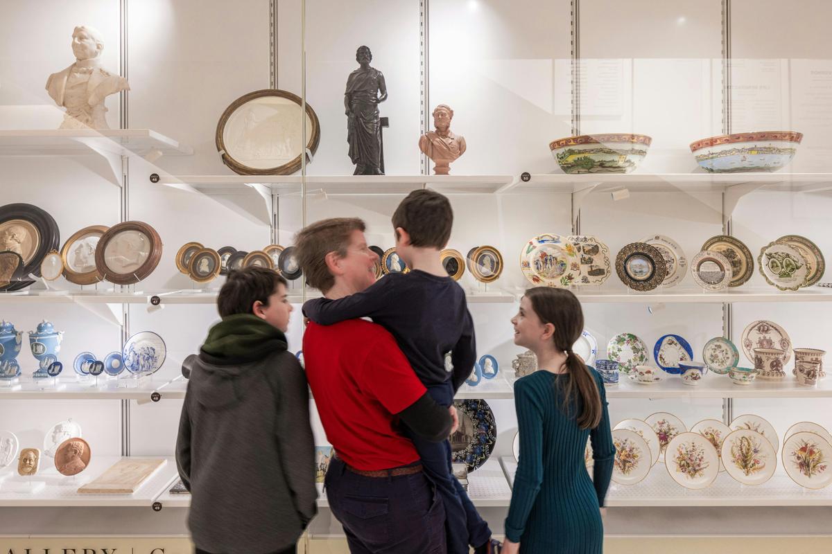 Father with children looking at objects in a display case.