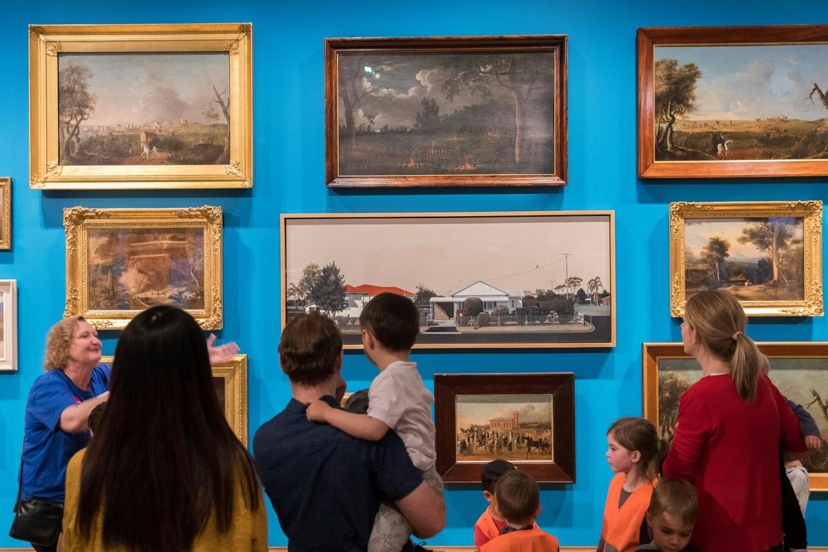 Parents and children looking at art in a gallery.