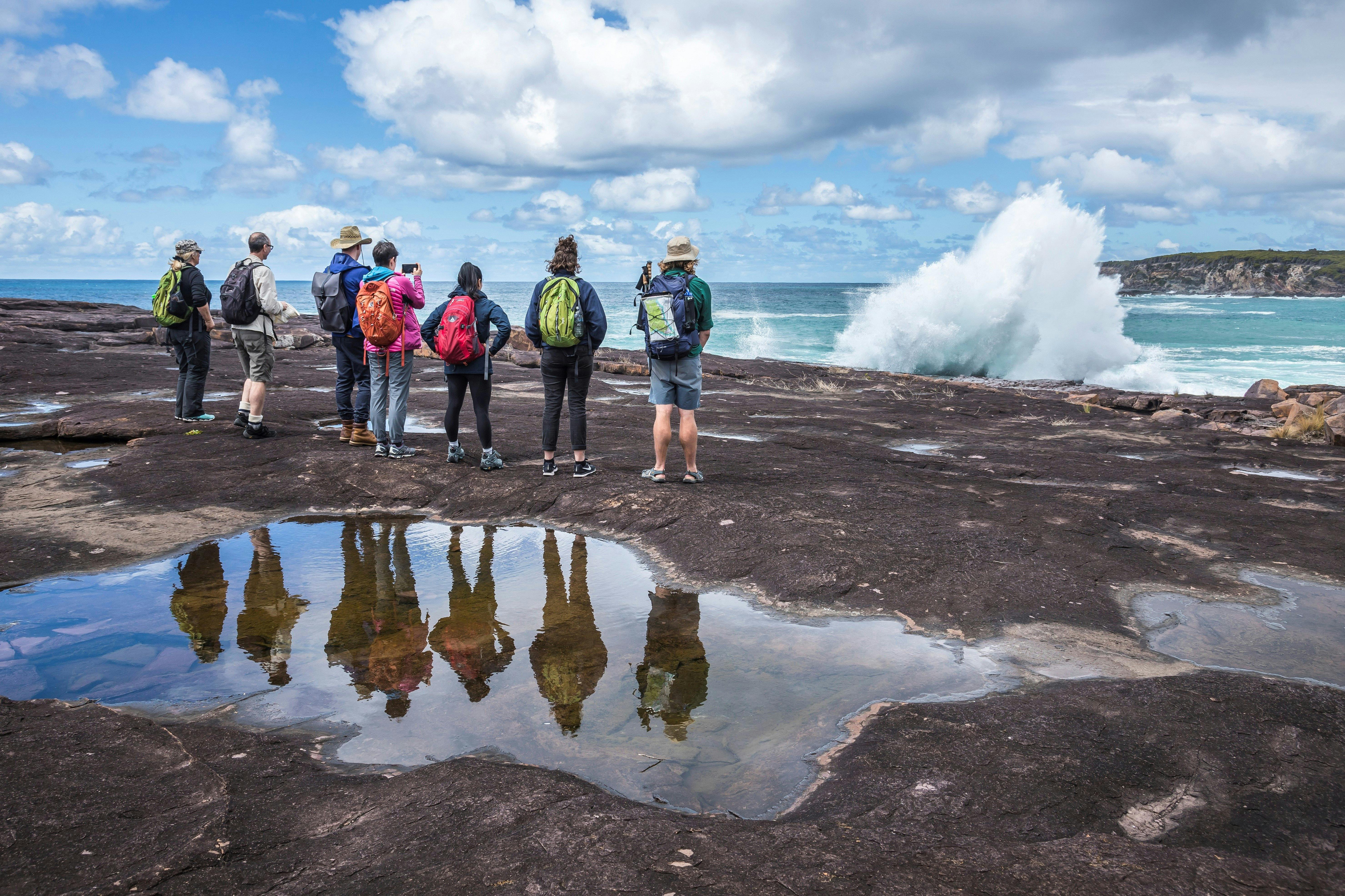 Walking group watching waves crash on the sea cliffs