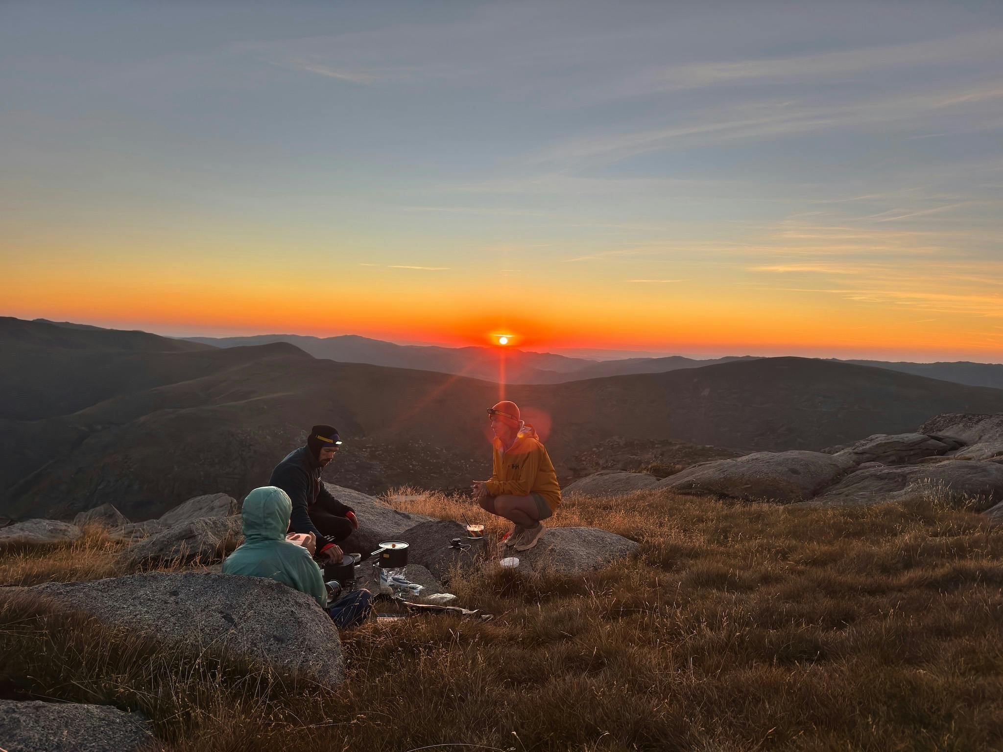 Hikers looking at the sunset over the mountains.
