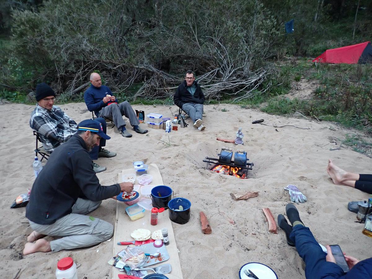 Guide cooking evening meal beside river