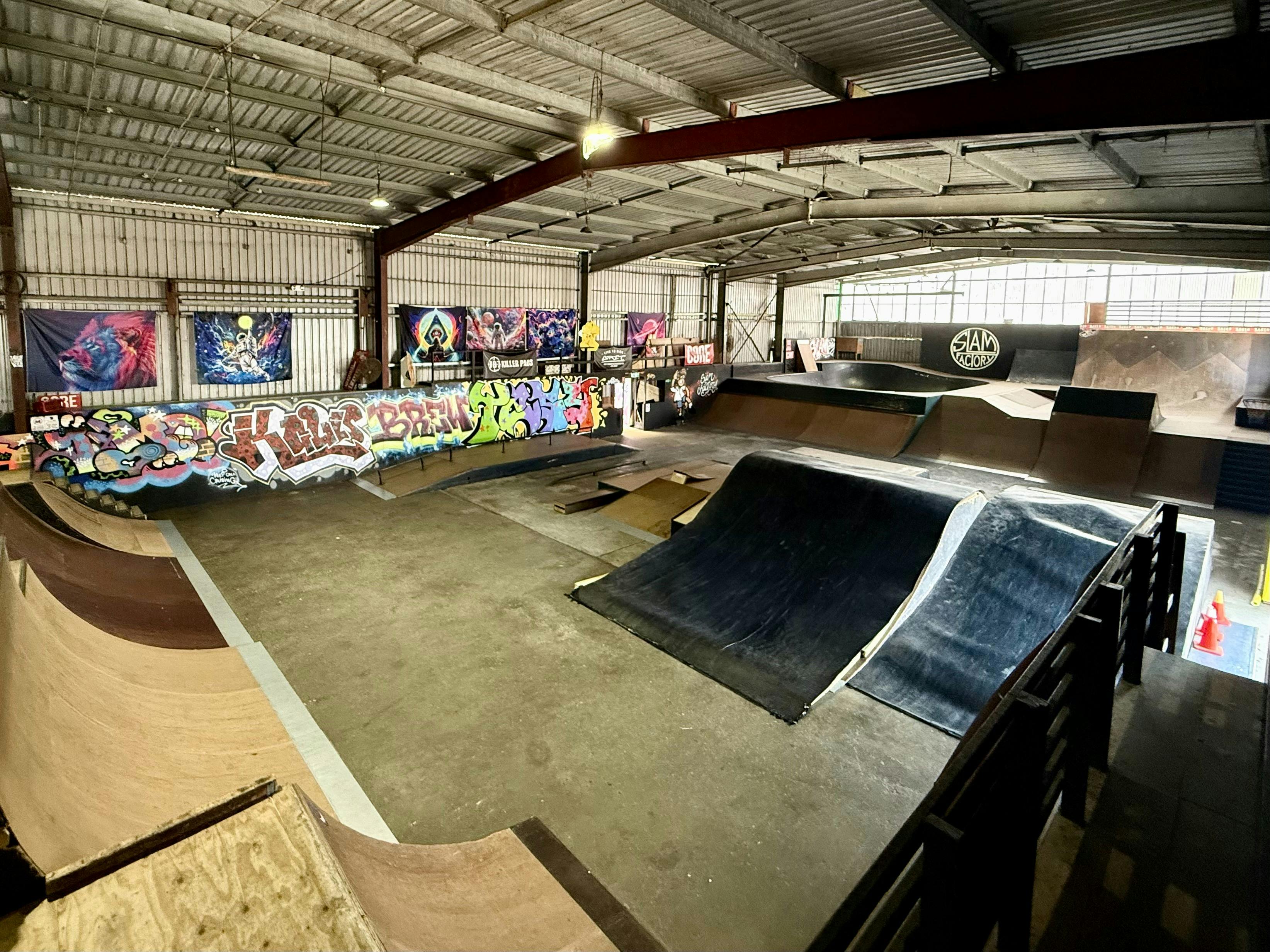 Wide view of Slam Factory’s main ramps and graffiti-lined indoor park.