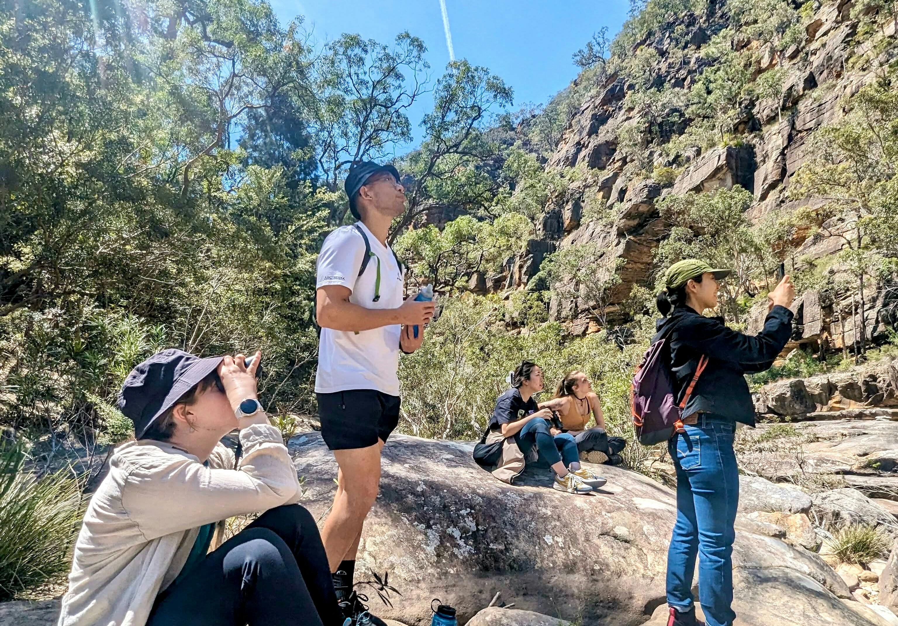 A group of tourists use binoculars to observe geological formations.