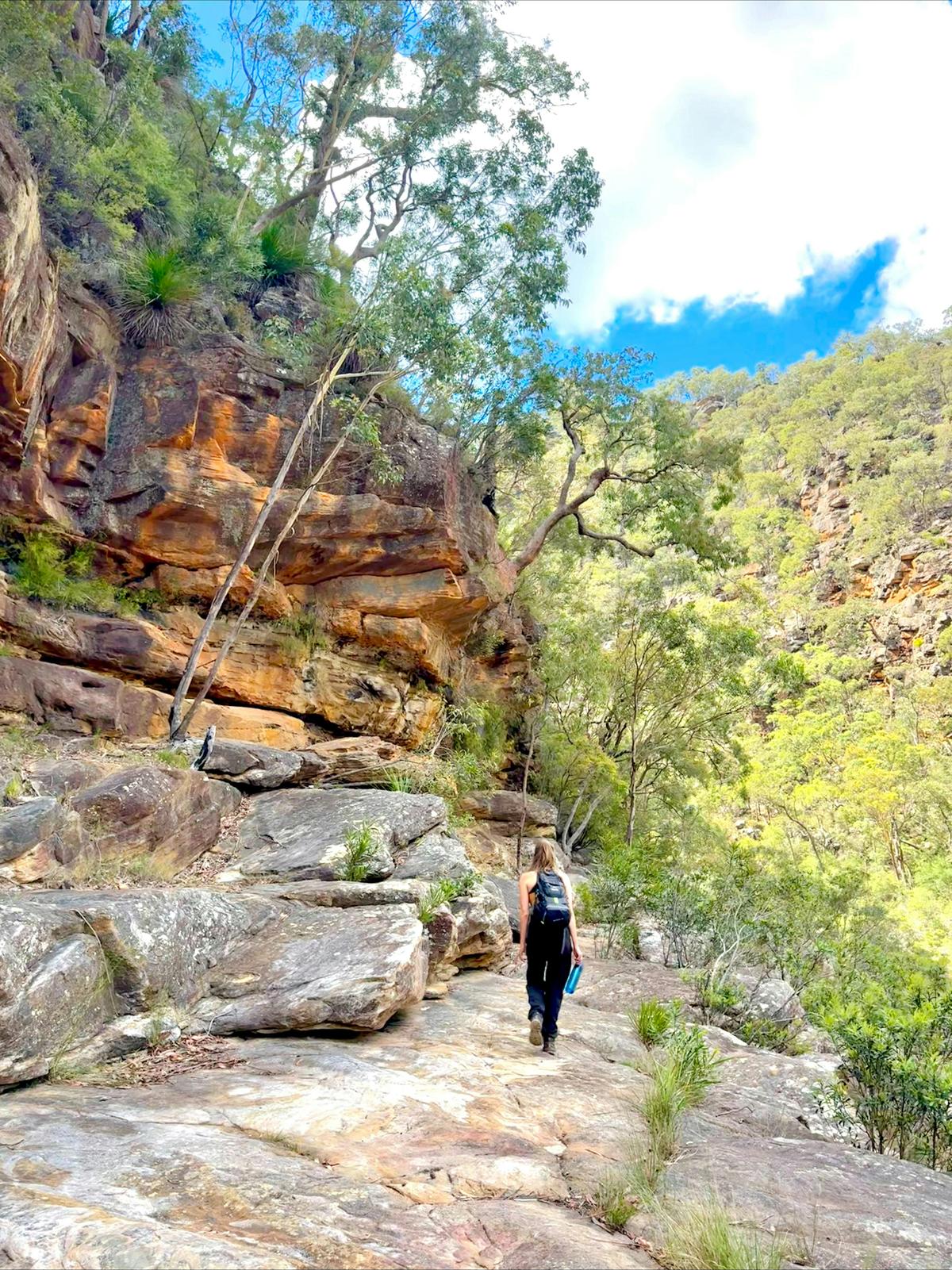 The guide walks along a rocky path in the gorge