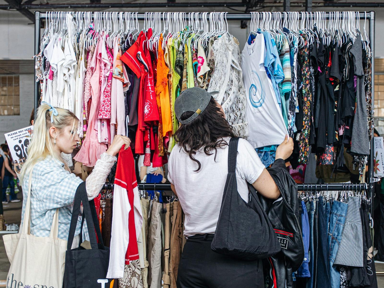 people shopping off of a large colourful clothing rack