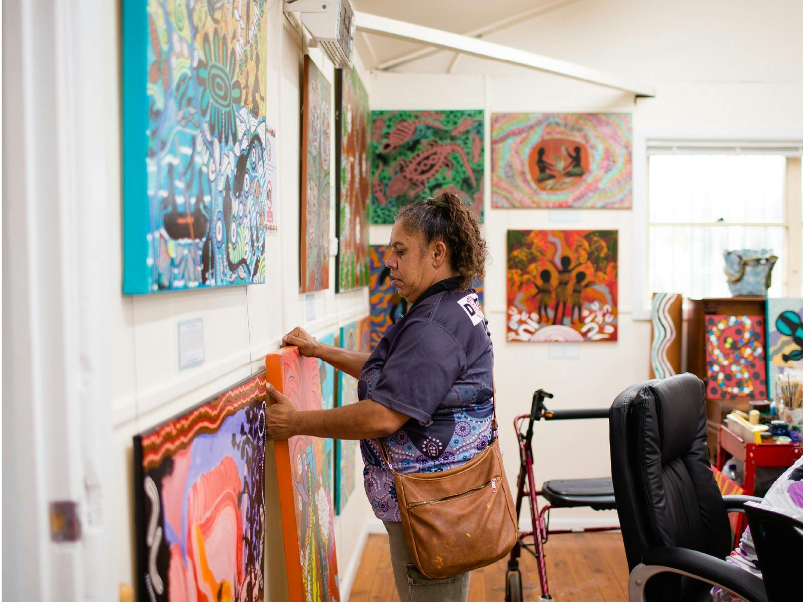 Coomaditchie staff member hanging artworks for exhibition