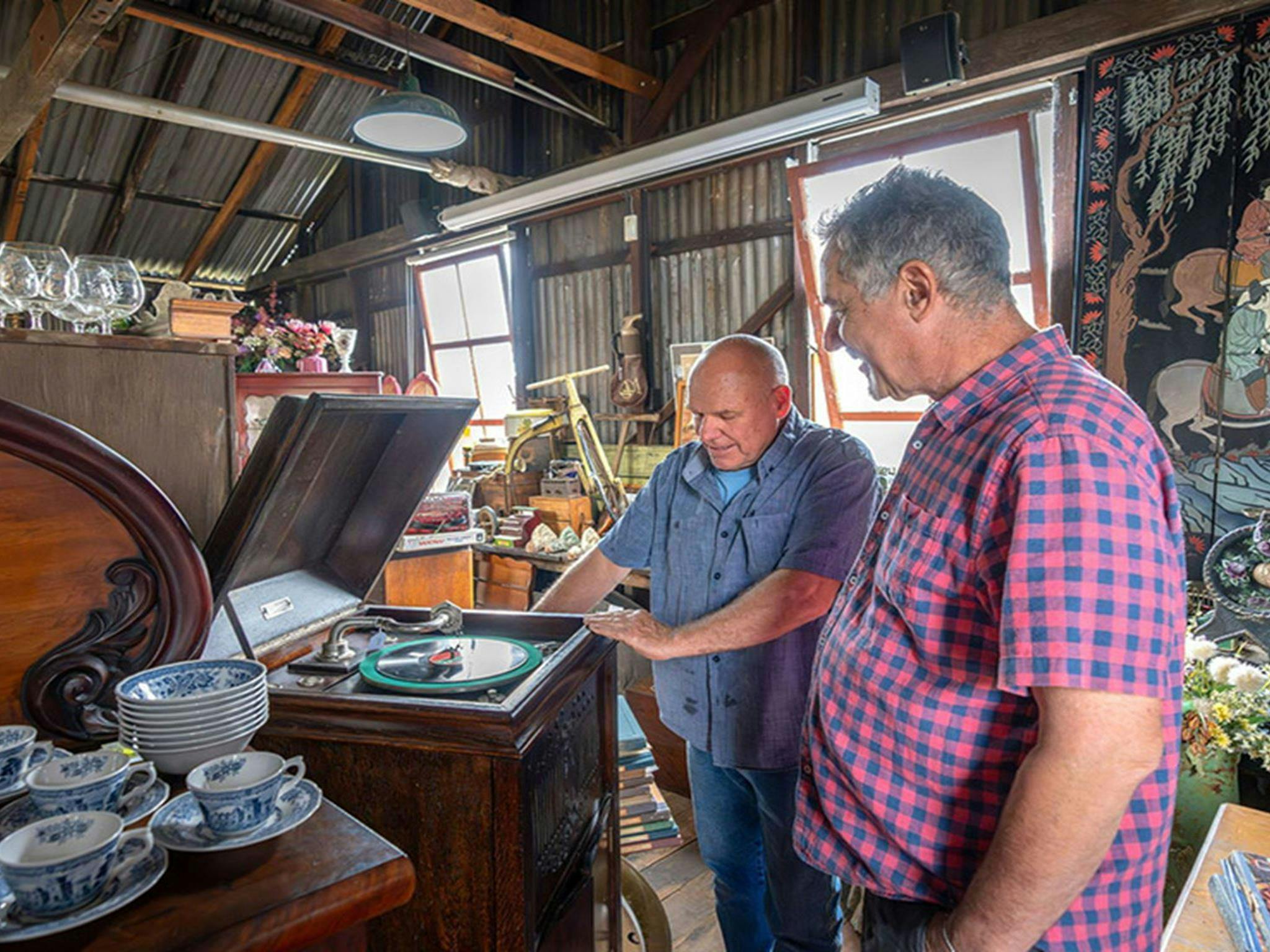 2 people looking at an antique record player inside the old Corneys Garage, now Gold Rush Antiques