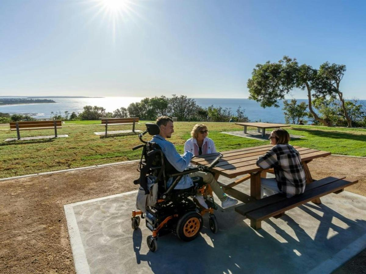 A group of friends at one of the accessible picnic tables at Crackneck Point lookout in Wyrrabalong