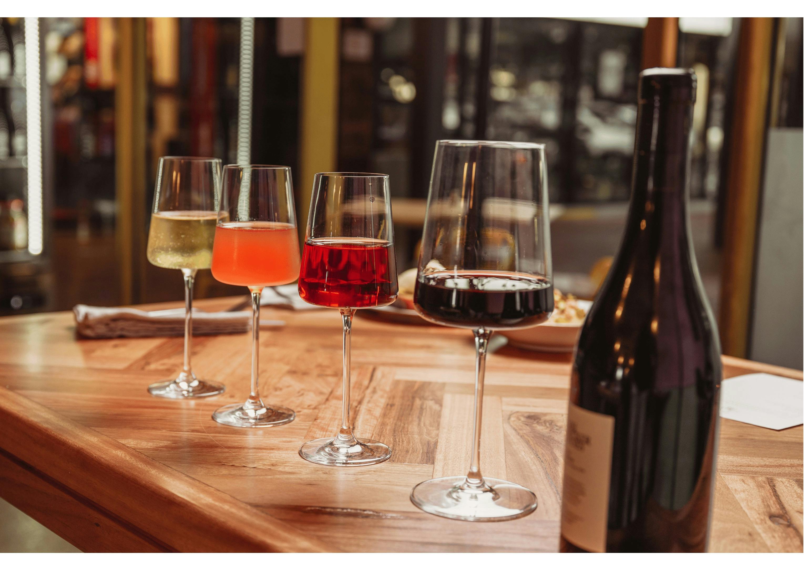 A row of four wine glasses - white, orange, Rose and red on a beautiful wooden table