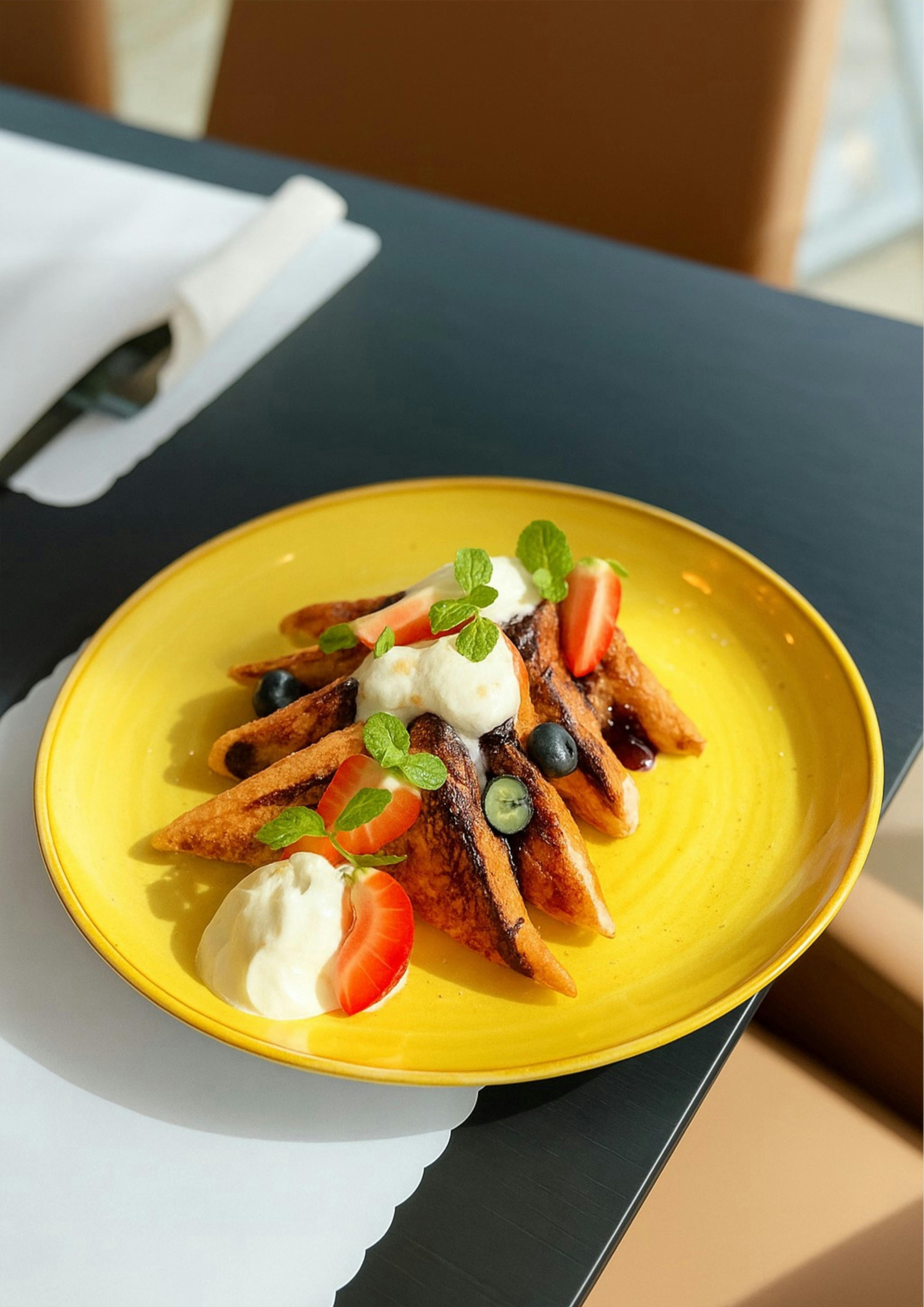 : Esteria French toast with fresh berries, cream, and mint — a vibrant breakfast favourite.