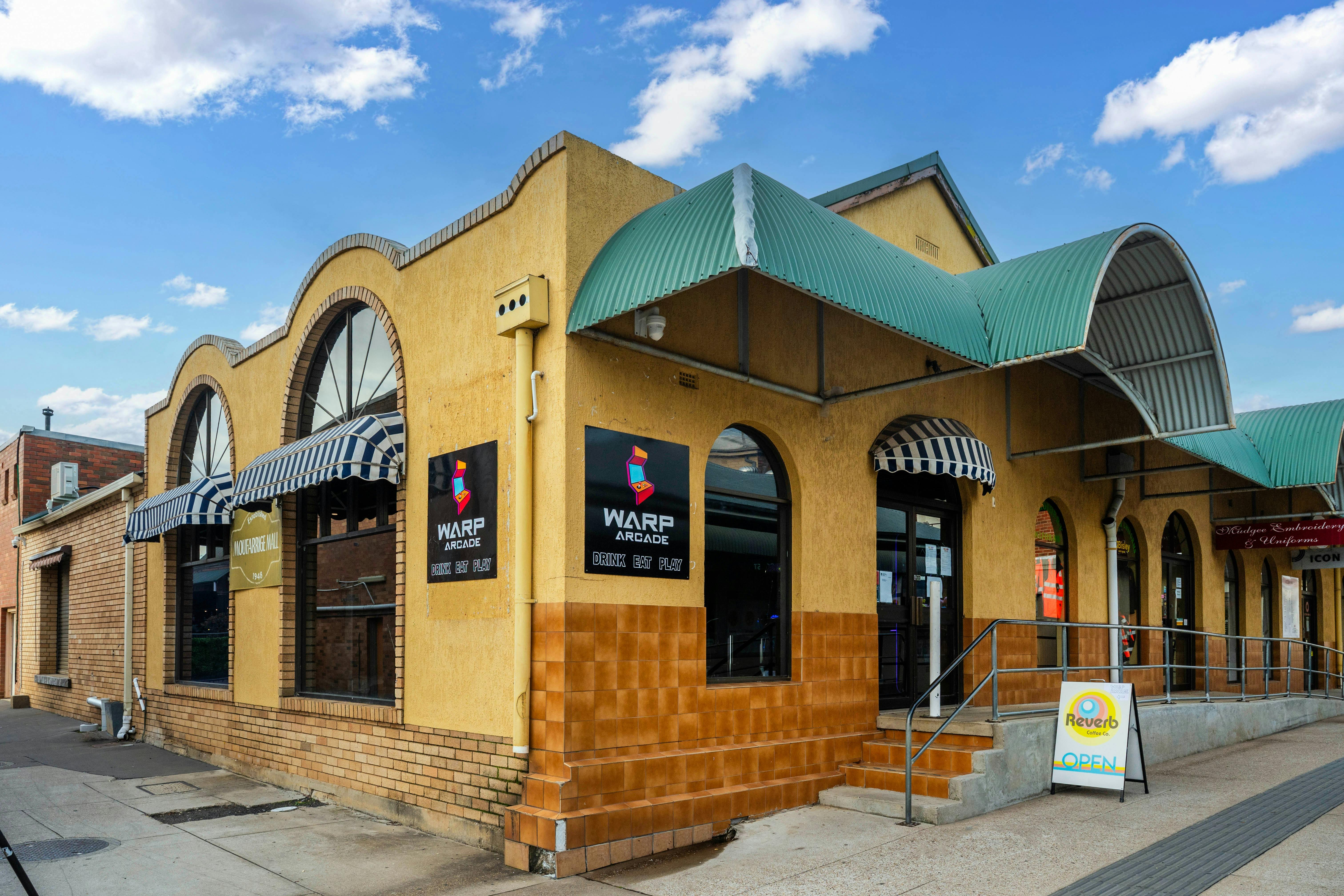 Exterior of Warp Arcade building with yellow walls, arched windows and the Warp Arcade signage