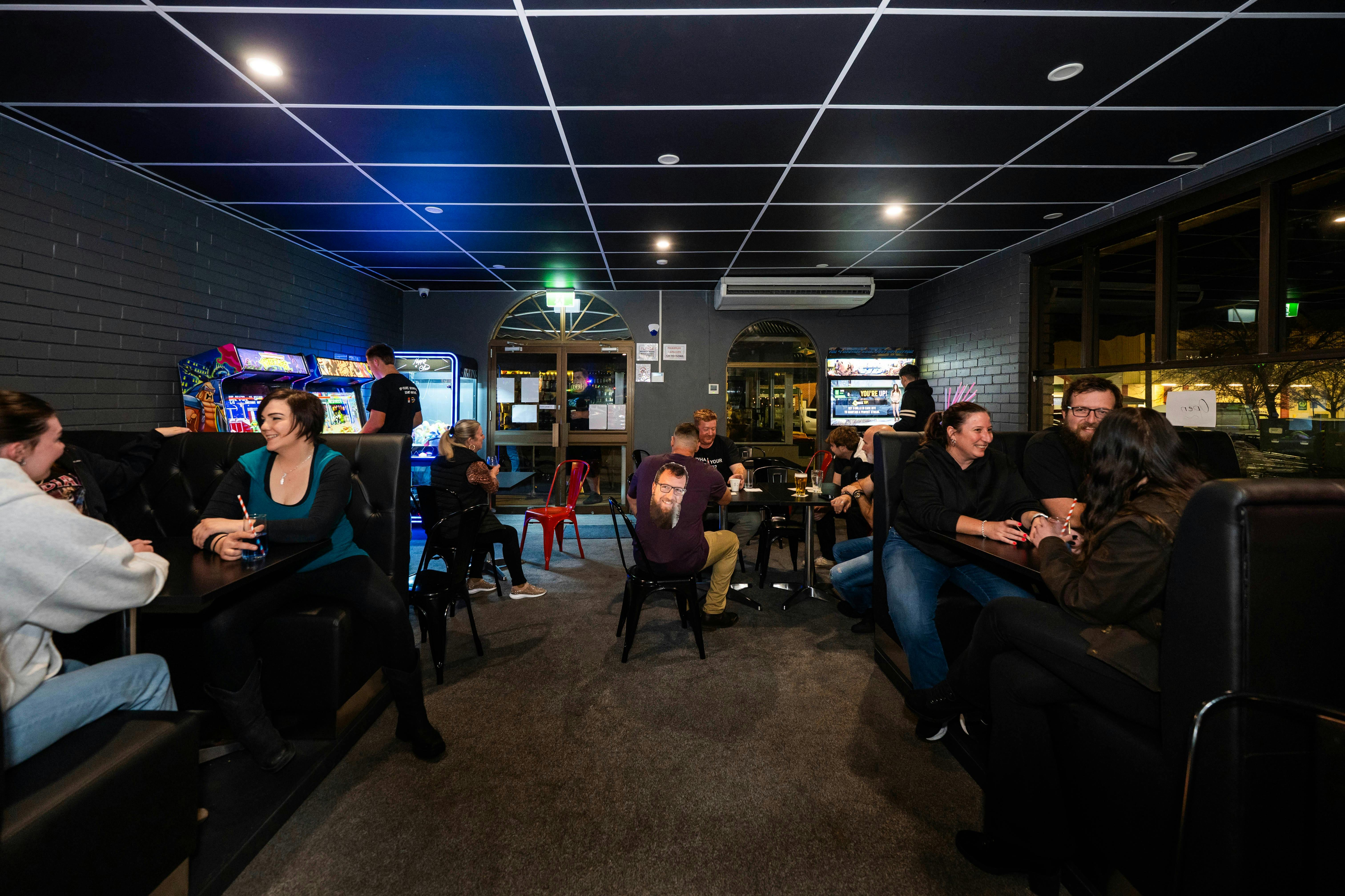 Wide view of the Warp Arcade dining floor with multiple arcade machines and neon lighting