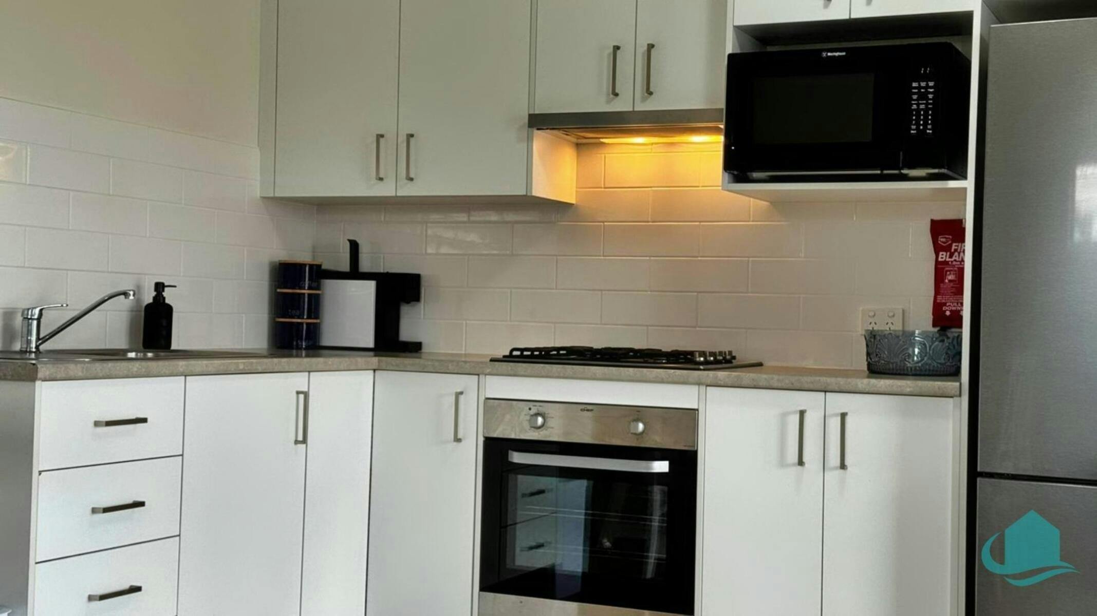 Kitchenette with full sized fridge, microwave, oven and cooktop