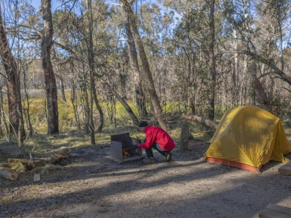 A man tends to the wood barbecue next to his tent at Barokee campground in Cathedral Rock National